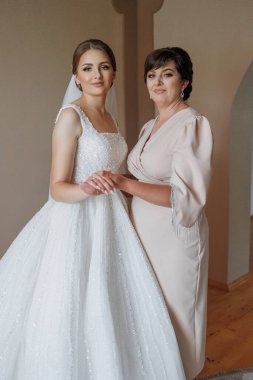 Gelinlikli bir kadın yaşlı bir kadının yanında duruyor.