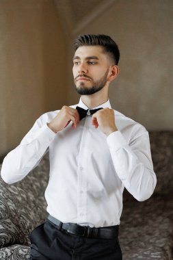 Beyaz gömlekli ve siyah kravatlı bir adam papyonunu bağlamaya hazırlanıyor. Görüntünün bulanık bir kalitesi var. Bu da ona rüya gibi ya da gerçeküstü bir his veriyor.