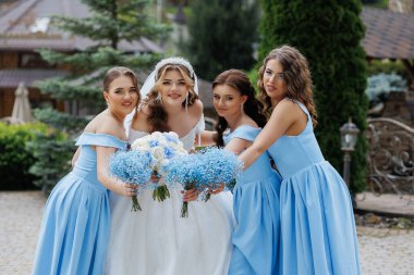 Mavi elbiseli bir grup kadın resim için poz veriyor. Kadınlardan biri beyaz peçe takıyor.