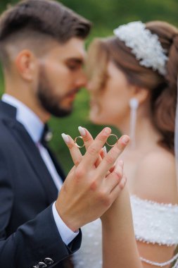 Bir adam ve bir kadın ellerinde yüzükler tutuyor, muhtemelen evleniyorlar. Kadın gelinlik giyerken adam takım elbise ve kravat takıyor. Aşk ve bağlılık kavramı