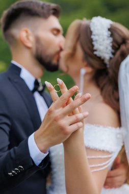 Bir adam ve bir kadın evlilik yüzüğü takan bir adamla öpüşüyor ve el ele tutuşuyorlar. Çiftler arasındaki sevgi ve bağlılık kavramı