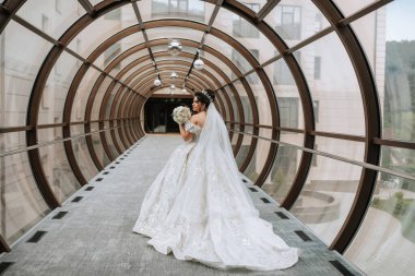 Beyaz elbiseli bir kadın tünelde duruyor. Elinde bir buket çiçek tutuyor.