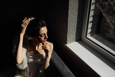 Gelinlik giymiş bir kadın küvette saçları topuz şeklinde oturuyor. Sahne zarif ve romantik.