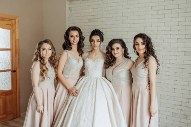 Beş kişilik bir grup beyaz bir duvarın önünde poz veriyor. Hepsi elbise giyiyor ve kameraya gülümsüyorlar. Sahne mutlu ve kutlama dolu.