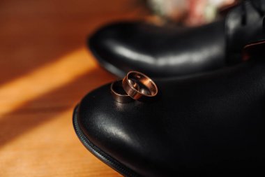 Bir çift alyans siyah bir ayakkabının üzerinde. Yüzükler bakırdan yapılmış ve ayakkabının tabanına yerleştirilmiş.