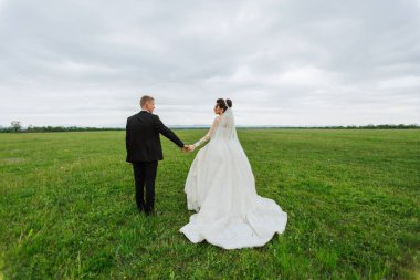 Bulutlu bir günde bir gelin ve damat tarlada yürüyor. Gelin beyaz bir elbise giyiyor ve damat siyah bir takım elbise giyiyor. El ele tutuşuyorlar ve birlikte vakit geçirmekten zevk alıyor gibiler.