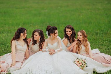 Beş kadından oluşan bir grup çimlerin üzerinde oturuyor, içlerinden biri gelinlik giyiyor. Gelin nedimeleriyle çevrili ve hepsi gülümsüyor ve birbirlerinin arkadaşlığından keyif alıyorlar.
