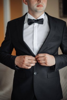 Siyah takım elbiseli ve beyaz gömlekli bir adam papyonunu bağlamaya hazırlanıyor. Formalite ve zarafet kavramı. Çünkü adam smokin giymiş ve özel bir olaya hazırlanıyor.