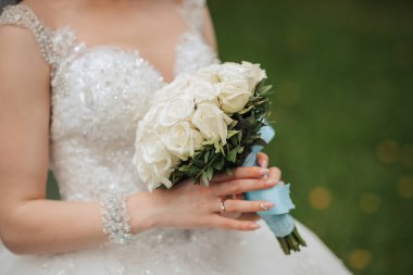 Bir gelin elinde bir buket beyaz gül tutuyor. Zarafet ve romantizm kavramı