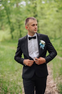 Siyah takım elbiseli ve beyaz gömlekli bir adam tarlada yürüyor. O, yakasında mavi bir papyon ve mavi bir çiçek takıyor. Zarafet ve incelik kavramı