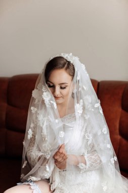 Beyaz peçeli bir kadın kanepede oturuyor.