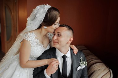 Bir adam ve bir kadın kanepede birbirlerine sarılıyorlar. Adam takım elbise ve kravat takıyor.