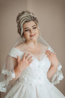 Beyaz gelinlikli bir kadın resim için poz veriyor. O bir peçe takıyor ve kolları omuzlarında. Mutluluk ve kutlama kavramı