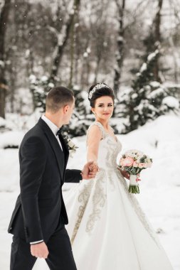 Bir gelin ve damat karda yürüyorlar, gelin bir buket tutuyor. Gelin beyaz bir elbise giyiyor ve damat bir takım elbise giyiyor. Sahne karlı bir ormanda geçiyor.