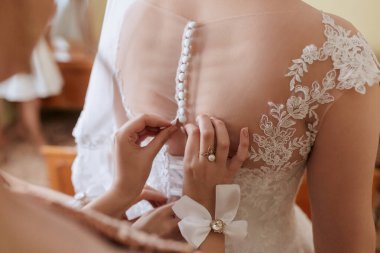 Bir kadın düğün için hazırlanıyor ve elbisesini düzeltiyor.