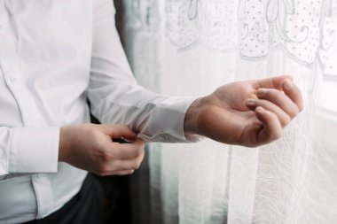 Bir adam giyiniyor ve gömleğini düzeltiyor. Hazırlık kavramı ve detaylara dikkat