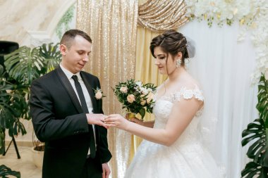 Bir erkek ve bir kadın evleniyor. Gelin beyaz bir elbise giyiyor.