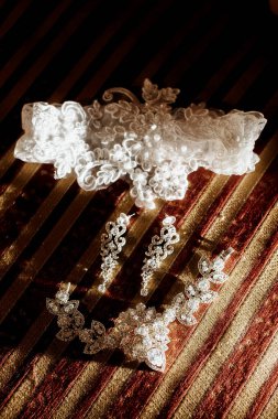 Beyaz bantlı beyaz dantel bir tren kırmızı ve altın çizgili bir arka plandadır. Tren dantelden yapılmıştır ve incilerle süslenmiştir.