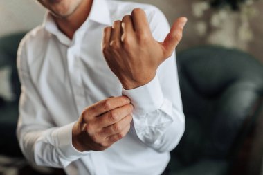 Bir adam giyiniyor ve gömleğini düzeltiyor. Formalite kavramı ve detaylara dikkat