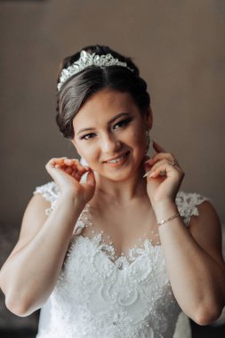 Bir kadın taç takıyor ve gülümsüyor. O, bir düğün için hazırlanıyor. İmajın mutlu ve kutlama havası var.