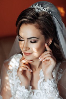 Kafasında peçesi ve yüzünde gülümsemesi olan bir kadın. Beyaz bir elbise giyiyor ve elleri yüzünde.