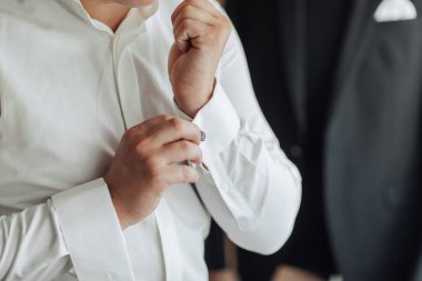 Bir adam takım elbise ve beyaz gömlek giyiyor. O bir kravat takıyor ve gömleğini düzeltiyor.