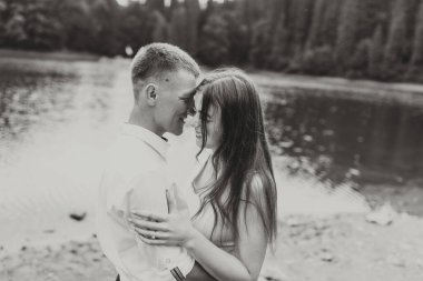 Bir çift yağmurda sarılıyor, erkeğin gömleği ıslak ve kadının saçı damlıyor.