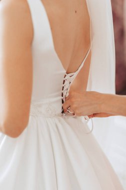 Bir kadın elbisesini bir kadın değiştiriyor. Elbise beyaz ve dantelli.