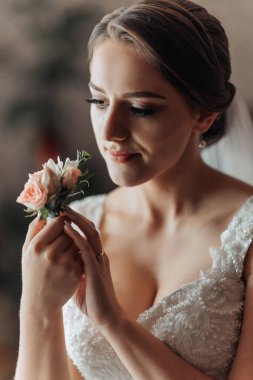Bir kadın elinde bir çiçek tutuyor. O bir gelinlik giyiyor ve yakasına bir çiçek taktırıyor. Zarafet ve kutlama kavramı