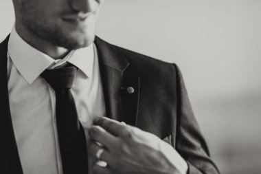 Takım elbiseli bir adam kravatını düzeltiyor. Formalite ve profesyonellik kavramı. Çünkü adam takım elbise ve kravat giymiş.