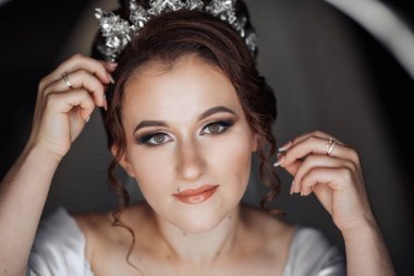 Kafasında taç olan bir kadın. Beyaz bir elbise giyiyor ve saçları topuz şeklinde.