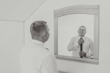 Bir adam kravatını aynanın önüne bağlamaya hazırlanıyor. Resmin nostaljik ve melankolik bir havası var. Adam yansımasına bakıyor ve resmi bir olaya hazırlanıyor.