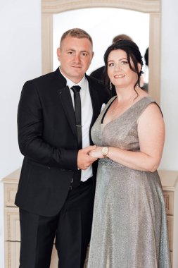 Bir adam ve bir kadın resim için poz veriyorlar. Kadın elbise giyerken adam takım elbise ve kravat takıyor. İkisi de gülümsüyor ve mutlu görünüyorlar. Zarafet ve incelik kavramı