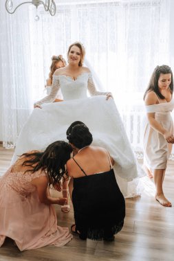 Bir gelin nedimeleriyle düğününe hazırlanıyor. Sahne neşeli ve kutlayıcıdır.