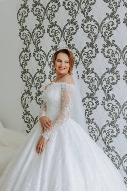 Beyaz gelinlikli bir kadın resim için poz veriyor. Gülümsüyor ve mutlu.