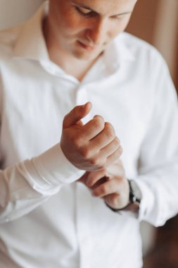 Beyaz gömlekli bir adam kollarını düzeltiyor. Formalite ve detaylara dikkat etme kavramı. Adamın gömleğine tam oturduğundan emin olmak için özen göstermesi gerekiyor.