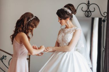 Bir gelin ve nedimesi düğün için hazırlanıyorlar. Gelin beyaz bir elbise ve duvak takarken nedime pembe bir elbise giyiyor.