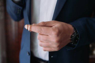 Takım elbiseli ve elinde yüzük tutan bir adam. Yüzük bir alyans.