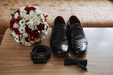 Bir adamın ayakkabıları ve kemeri bir buket çiçeğin yanındaki masada sergilenir. Adam özel bir durum için hazırlanıyor. Çiçekler ve ayakkabılar da aşkının sembolü.