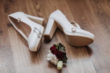 Yerde kırmızı bir gül olan bir çift beyaz ayakkabı. Ayakkabılar elmaslarla süslenir ve bir buket kırmızı gülün yanına yerleştirilir. Beyaz ayakkabılar gibi zarafet ve romantizm kavramı