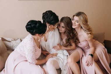 Bir grup kadın bir kanepede oturuyor, içlerinden biri gelinlik giyiyor. Hepsi gülümsüyor ve birbirlerinin arkadaşlığından zevk alıyor gibi görünüyorlar. Sahne sıcak ve dostane.