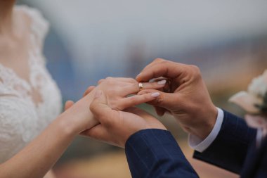 Bir erkek ve bir kadın evleniyor ve erkek kadının parmağına yüzük takıyor.