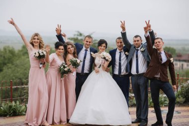 Bir grup insan, bir gelin ve damat, bir tepede fotoğraf için poz veriyorlar.