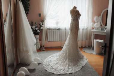 Bir gelin, aynası ve penceresi olan bir odada düğününe hazırlanıyor. Oda balonlarla ve çiçeklerle süslenmiş.