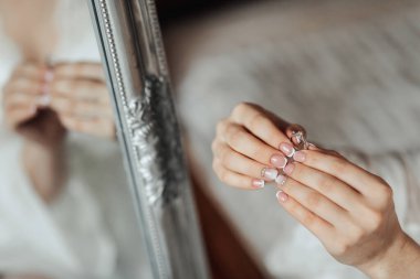 Bir kadın elinde bir yüzük tutuyor ve aynadaki yansımasına bakıyor.