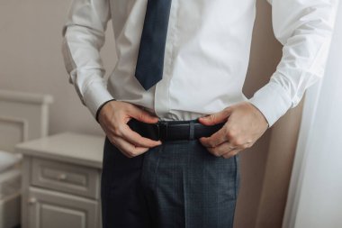 Takım elbiseli bir adam kemerini ayarlıyor. Formalite ve profesyonellik kavramı