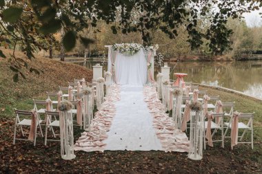 Beyaz çadırı ve beyaz halısı olan bir parkta bir düğün töreni yapılacak. Sandalyeler sıraya dizildi ve konuklar yerleşti.