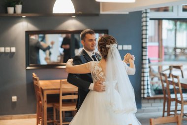 Bir adam ve bir kadın bir restoranda dans ediyorlar. Adam takım elbise giyiyor ve kadın da gelinlik giyiyor. Sahne romantik ve kutlayıcıdır.