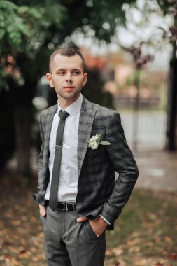 Takım elbiseli ve kravatlı bir adam yakasında çiçekle bir tarlada duruyor. Zarafet ve entelektüellik anlayışı, çünkü adam resmi giyinmiş.