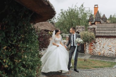 Bir gelin ve damat bir kalenin önünde bir patikada yürüyorlar. Gelin beyaz bir elbise giyiyor ve damat bir takım elbise giyiyor. El ele tutuşuyorlar ve mutlu görünüyorlar.